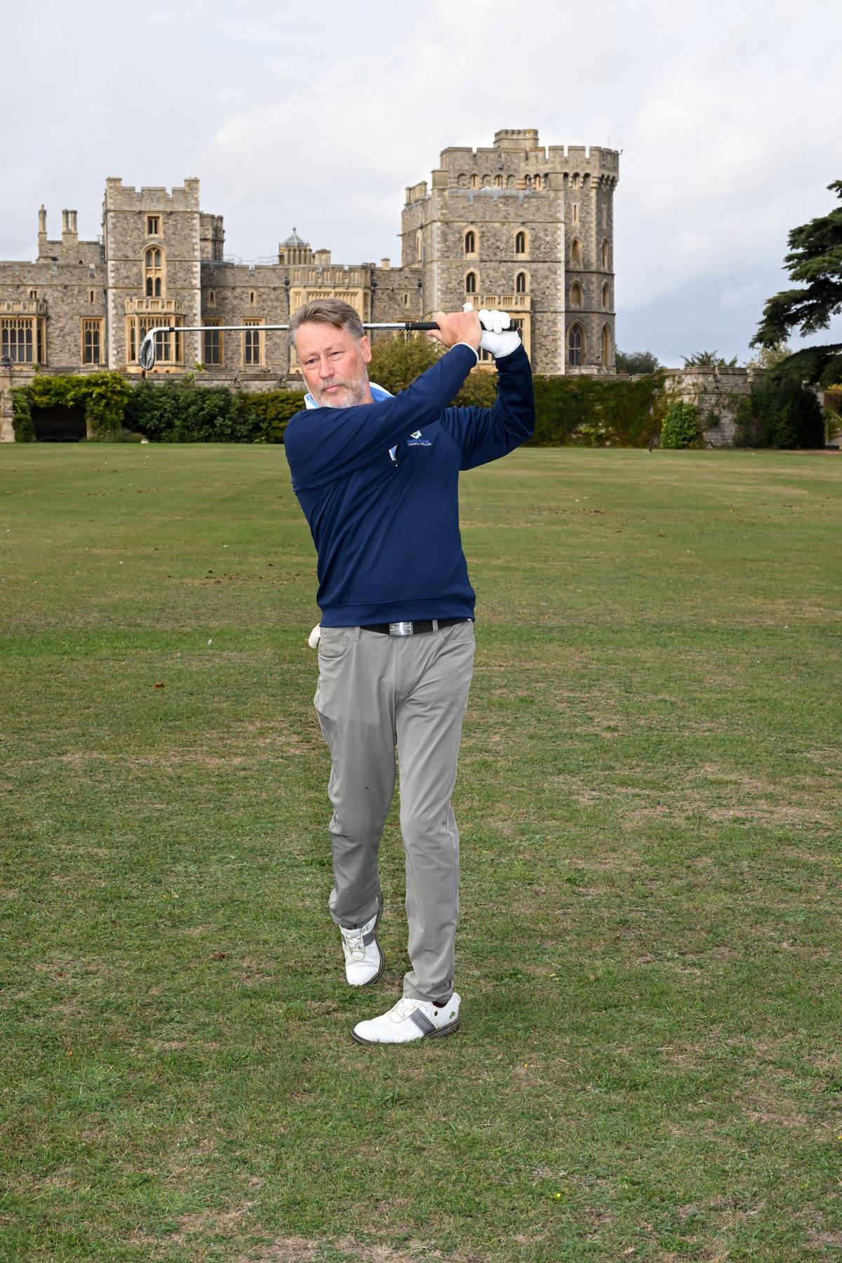 Andrew Stewart, 2026 winner, finishing his golf swing on the grass with Windsor Castle behind him